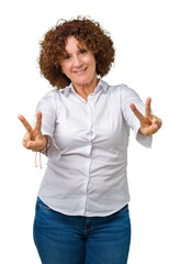 Beautiful middle ager senior businees woman over isolated background smiling looking to the camera showing fingers doing victory sign. Number two.