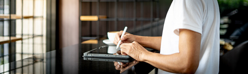 Young man holds a pen and writes on a tablet
