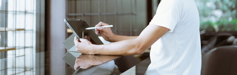 Young man holds a pen and writes on a tablet