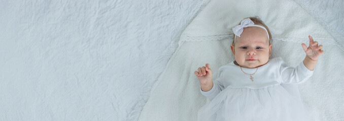 The sacrament of baptism of a child. The child is holding a cross.