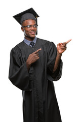 Young graduated african american man over isolated background smiling and looking at the camera pointing with two hands and fingers to the side.