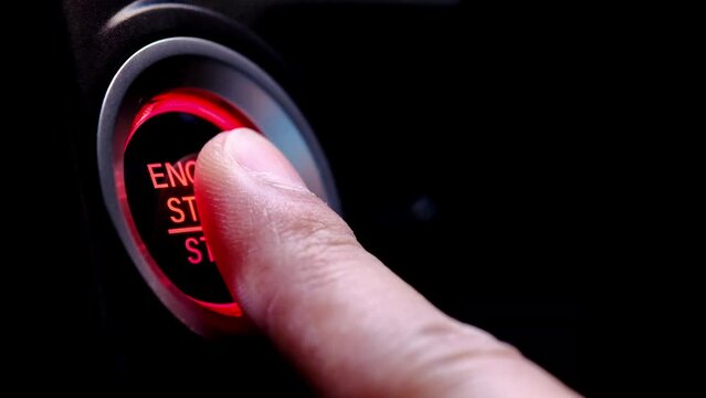 The driver's hand is pressing the car start button. Concept of transportation and technology	