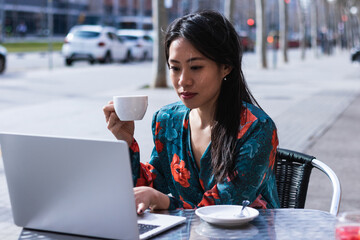 Thinking, drinking coffee and woman on laptop in cafeteria. Dream, computer and Asian freelancer...