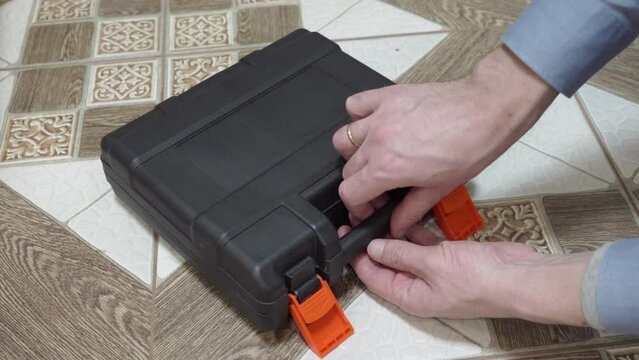 a man takes an electric screwdriver from a box, take a cordless drill from the black box and install the bit