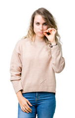 Beautiful young blonde woman wearing sweatershirt over isolated background mouth and lips shut as...