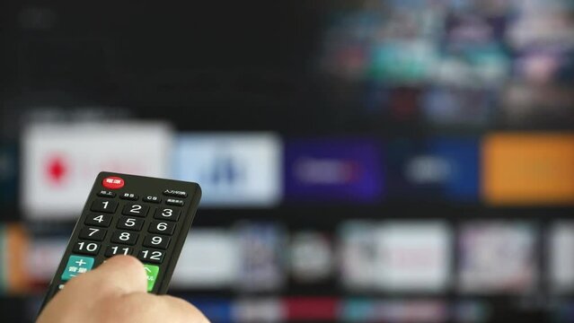 テレビのリモコンを操作する手元
