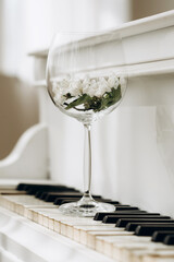 A glass with white flowers stands on the piano keyboard