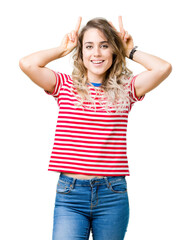 Beautiful young blonde woman over isolated background Posing funny and crazy with fingers on head as bunny ears, smiling cheerful