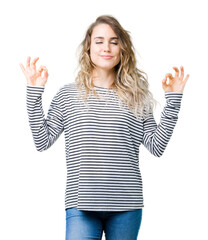 Beautiful young blonde woman wearing stripes sweater over isolated background relax and smiling with eyes closed doing meditation gesture with fingers. Yoga concept.