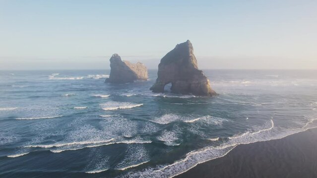 Sunrise shining over Wharariki beach with iconic rocky mountain on Tasman sea in archway islands at New Zealand