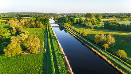 Ein ruhiger Kanal windet sich durch eine malerische Landschaft. Grüne Ufer und eine friedliche...