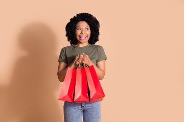 Photo of nice woman with afro hairstyle wear khaki t-shirt hold shopping bags look at sale empty...