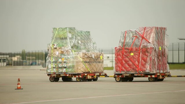 Two cargo pallets wrapped in nets on tarmac, ready for air transport, clear daylight, no people