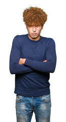 Young handsome man with afro hair skeptic and nervous, disapproving expression on face with crossed...
