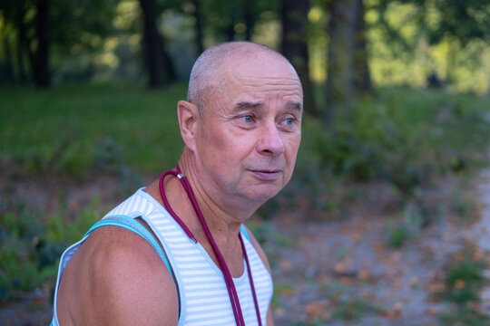 Close Up Male Face, Pretty Caucasian Mature Man 60-65 Years Old Smiling On Green Natural Background, Good Mood, Age-related Changes, Concept Mental Human Health, Optimism In Adulthood, Happy Years