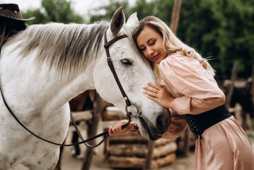 Beautiful blonde girl in a long dress with a white horse