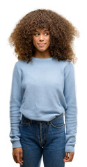 African american woman wearing a sweater smiling looking side and staring away thinking.