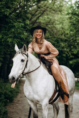 Fototapeta premium Beautiful blonde girl in a long dress with a white horse