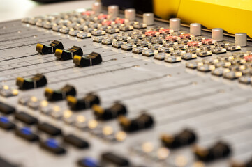 Professional audio mixing console closeup, detailed focus on sound adjustment knobs and sliders