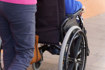 Obraz premium an unrecognizable woman pushing a wheelchair with a person sitting in it