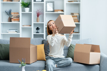 Young Woman Enjoying Moving Day At Home, Sitting On Couch With Cardboard Boxes, Expressing...