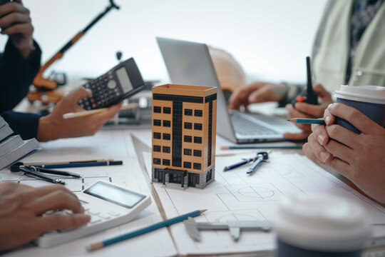 Skilled team of engineers collaborates in meetings, drafting blueprints for condos, apartments, houses. Negotiating costs, bids, and contracts, they ensure efficient cooperation on construction sites.