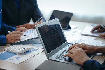 A professional business team meeting in formal suits, working at desks with financial papers, calculators, and laptops. Close-up of hands. Discussion on revenue, brand, sales, agenda, capital