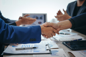 In a business team meeting, success is celebrated with a handshake. Hands close up, dressed in...