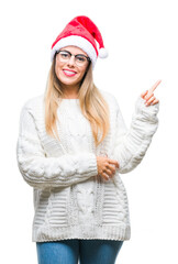 Young beautiful woman wearing christmas hat over isolated background with a big smile on face, pointing with hand and finger to the side looking at the camera.