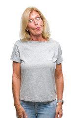 Fototapeta premium Middle age blonde woman over isolated background making fish face with lips, crazy and comical gesture. Funny expression.