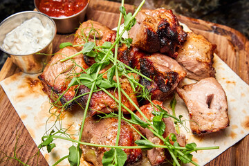 Pork shish kebab on pita bread with two types of sauces