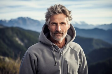 Portrait of a blissful man in his 50s wearing a zip-up fleece hoodie while standing against...