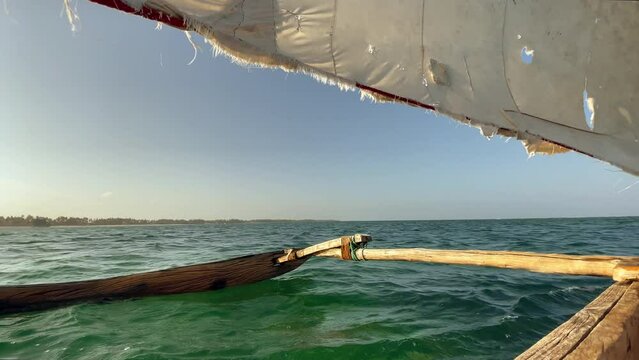 4K authentic wooden sailing fishing boat heading for open seas with rugged sail. Traveling, fishing lifestyle, tropical environment, indigenous peoples and remote places concept. Zanzibar, Tanzania.