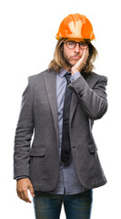 Young handsome architec man with long hair wearing safety helmet over isolated background thinking looking tired and bored with depression problems with crossed arms.