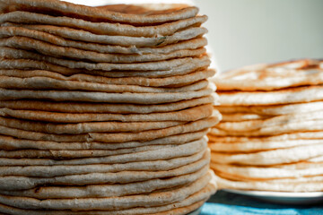 Flatbread lavash, chapati, naan, heap of tortilla on a blue background Homemade flatbread stacked.