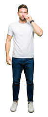 Handsome man wearing casual white t-shirt mouth and lips shut as zip with fingers. Secret and...