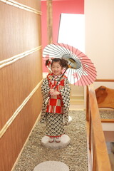 アンティークの着物を着た可愛い女の子が和傘を差して笑う