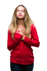 Fototapeta premium Young beautiful blonde woman wearing red sweater over isolated background smiling with hands on chest with closed eyes and grateful gesture on face. Health concept.