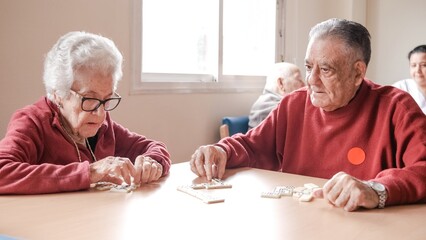 Senior friends playing dominoes game in nursing home