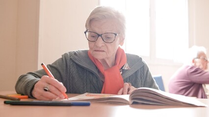 Elderly woman drawing in book with felt-tip pens in nursing home