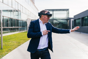 Executive in suit uses VR glasses to point at digital elements.