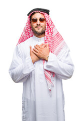 Young handsome man wearing keffiyeh over isolated background smiling with hands on chest with closed eyes and grateful gesture on face. Health concept.