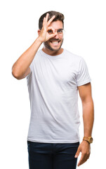 Fototapeta premium Young handsome man wearing glasses over isolated background doing ok gesture with hand smiling, eye looking through fingers with happy face.