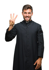 Young catholic christian priest man over isolated background showing and pointing up with fingers number three while smiling confident and happy.