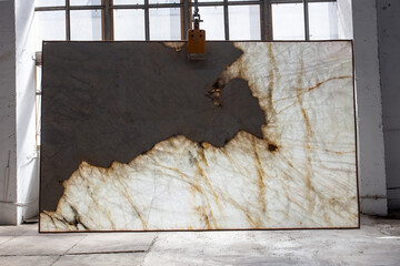 Picture of a marble slab on a hanger, shot in natural light, a cut of decorative marble in a warehouse, a large piece of marble. High Resolution. Backlit Brazil granite Patagonia extra