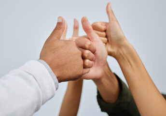 Thumbs up, hands together and team of people in studio with unity, collaboration and partnership. Winning, pride and group of employees with satisfaction gesture for solidarity by gray background.
