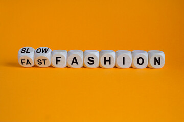 Fast or slow fashion symbol. Concept words Fast fashion and Slow fashion on wooden cubes. Beautiful wooden table orange background. Business fast or slow fashion concept. Copy space. - Powered by Adobe