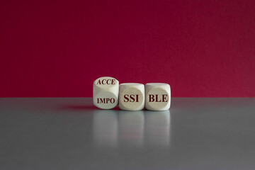 Symbol for inclusion. Turned a cube and changes the word impossible to accessible. Beautiful pink background, grey table.