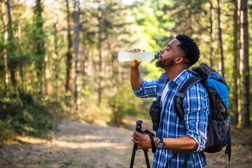 Young man enjoys hiking and drinking energy drink.	
