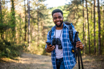 Young man enjoys hiking and using mobile phone in nature.	